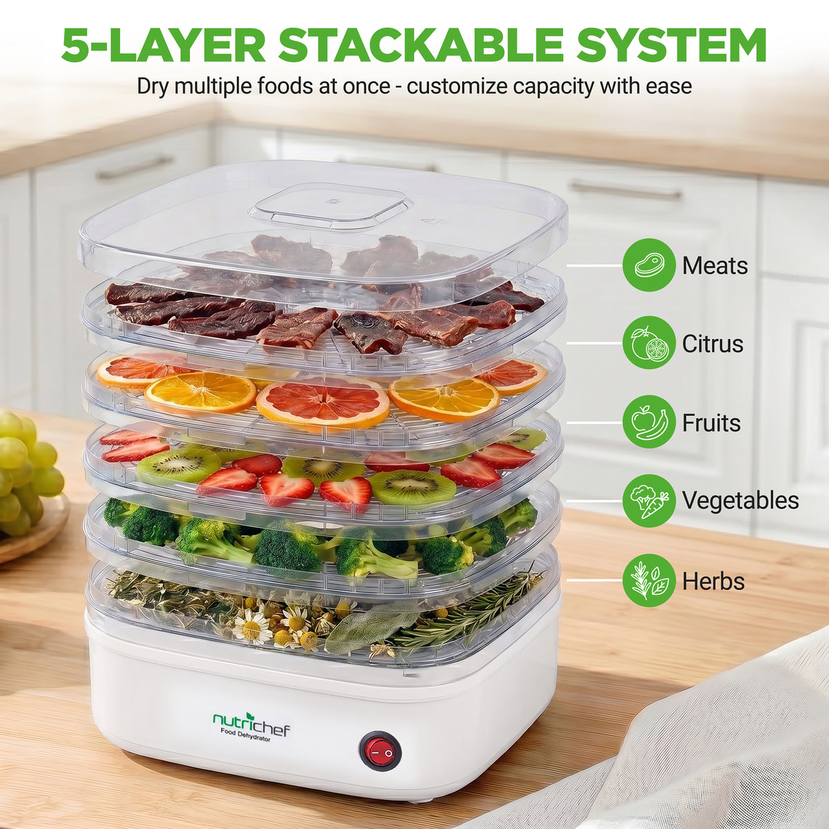 Nuvita food dehydrator with five layers of dried foods on a wooden surface.